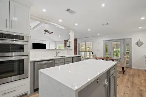 a large kitchen with kitchen island a sink and a stove top oven with wooden floor