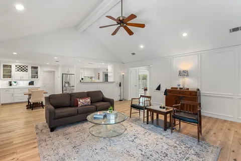 a living room with furniture and a dining table with wooden floor