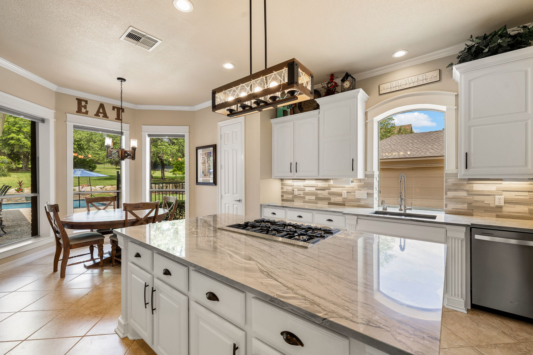 3609 Goodnight Trail Leander, TX 78641 - Photo 12 of 39 a kitchen with granite countertop a stove a sink a dining table and chairs