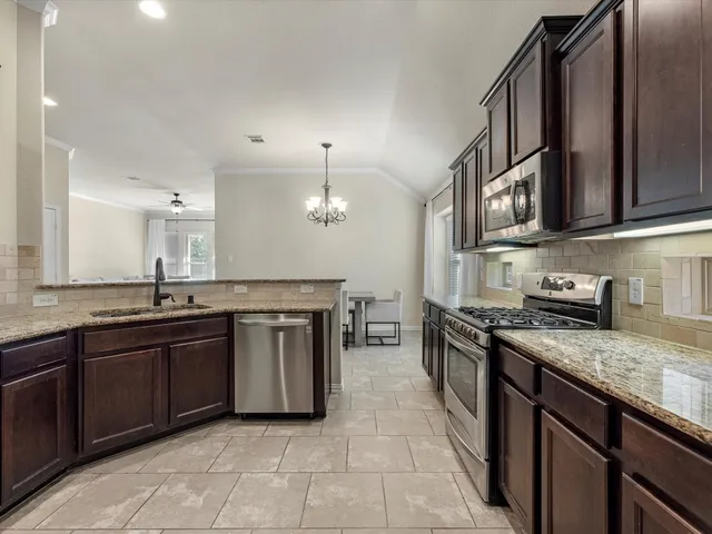 a kitchen with stainless steel appliances granite countertop a stove microwave and sink