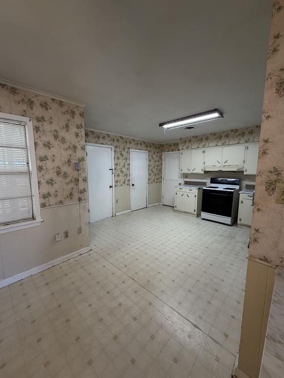 134 Hope Street Mansfield, LA 71052 - Photo 12 of 23 Eat in kitchen from LR featuring wallpapered walls, wainscoting, light floors, and ornamental molding
