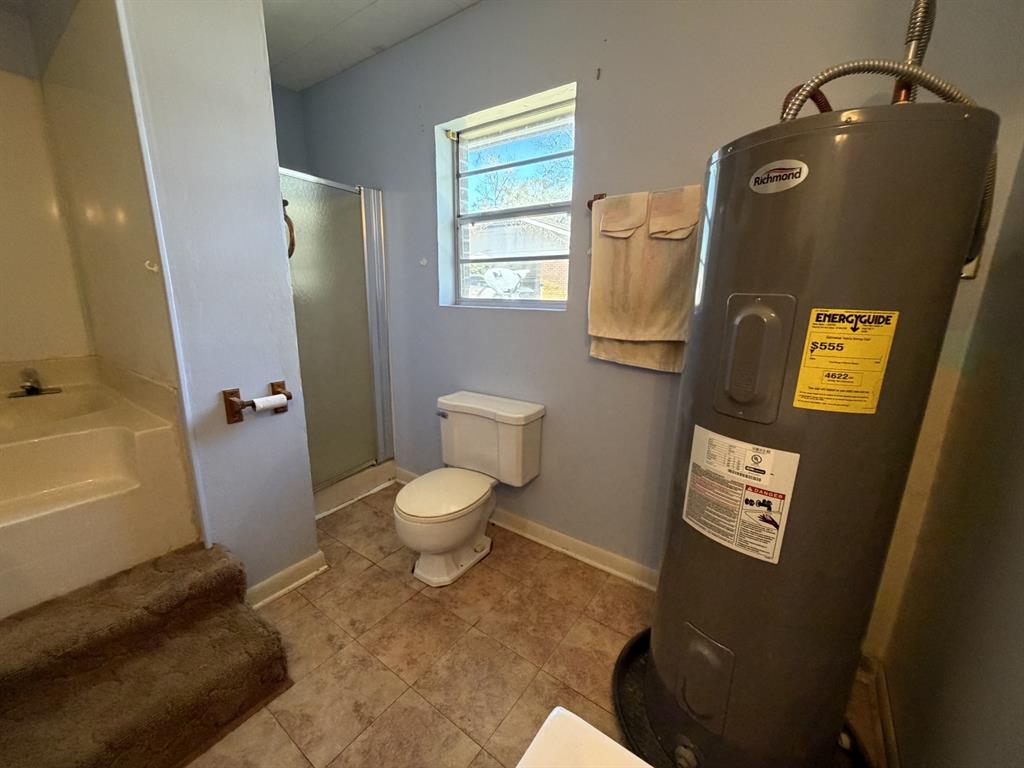 134 Hope Street Mansfield, LA 71052 - Photo 20 of 23 Master Bathroom with electric water heater, a stall shower, a bath, and light tile patterned floors