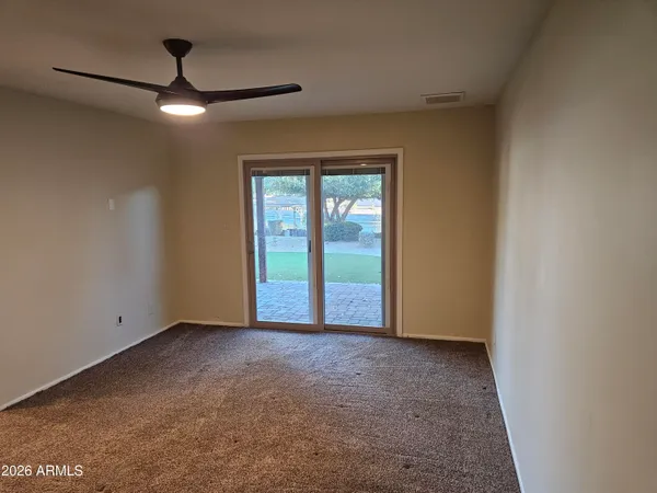 an empty room with chandelier fan and windows