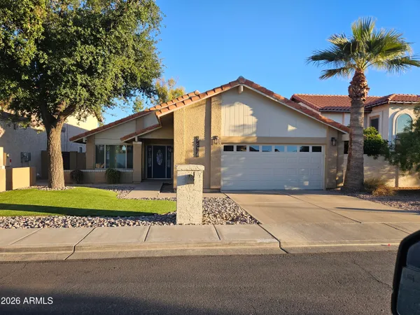 a front view of a house with a garden and trees