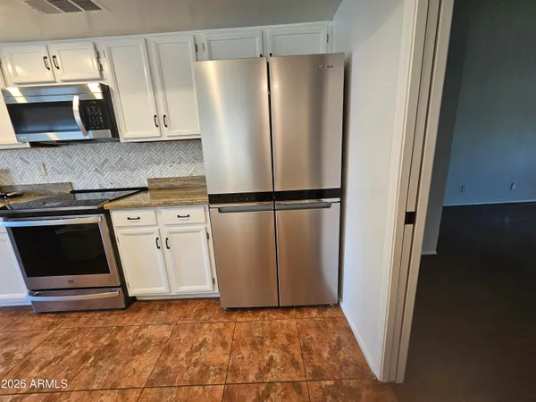 a kitchen with stainless steel appliances granite countertop a refrigerator a microwave a sink and cabinets