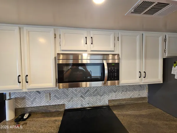 a kitchen with granite countertop a stove and a white cabinets