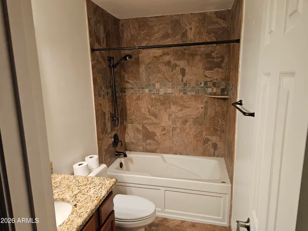 a bathroom with a granite countertop bathtub shower sink vanity and toilet
