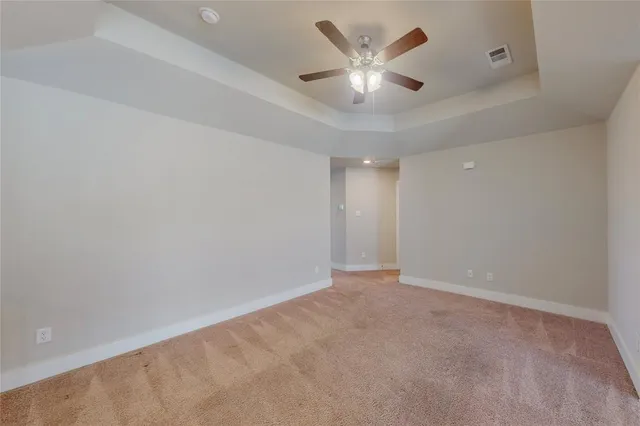 an empty room with a chandelier fan and windows