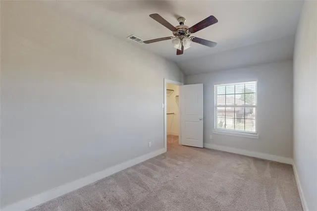 an empty room with a window and a fan