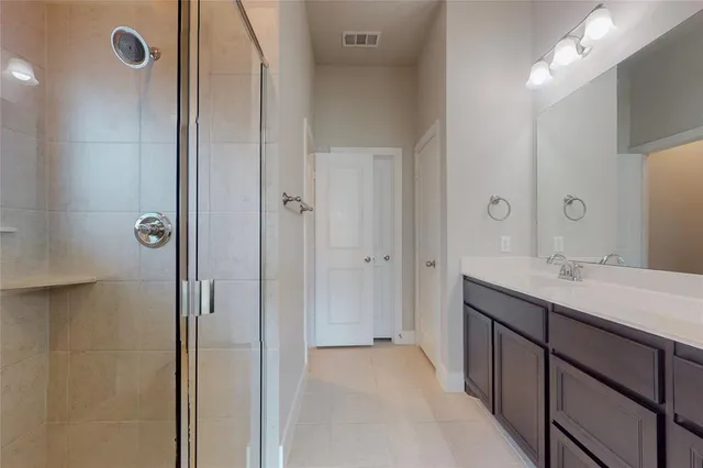 a spacious bathroom with a double vanity sink a mirror and shower