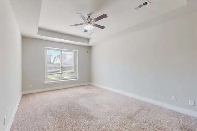 an empty room with chandelier fan and windows