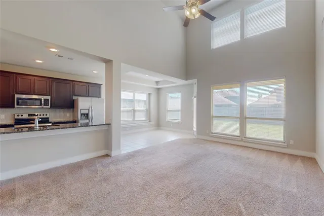 a large kitchen with stainless steel appliances granite countertop a refrigerator a stove a sink and a large window