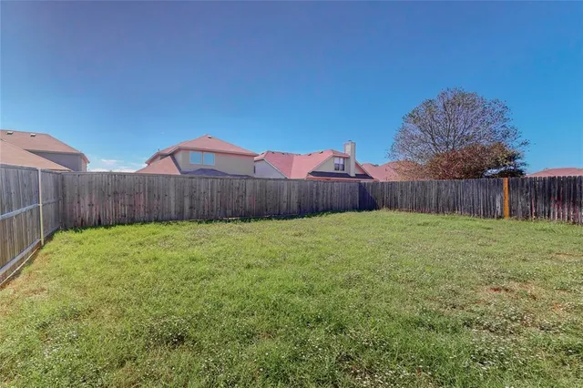 a view of a backyard with table and chairs and wooden fence