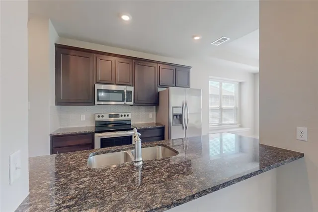 a kitchen with stainless steel appliances granite countertop a sink a stove counter space and cabinets