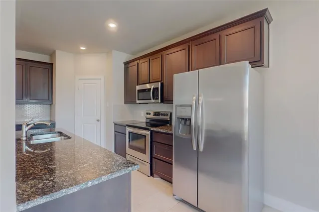 a kitchen with granite countertop a refrigerator and a sink