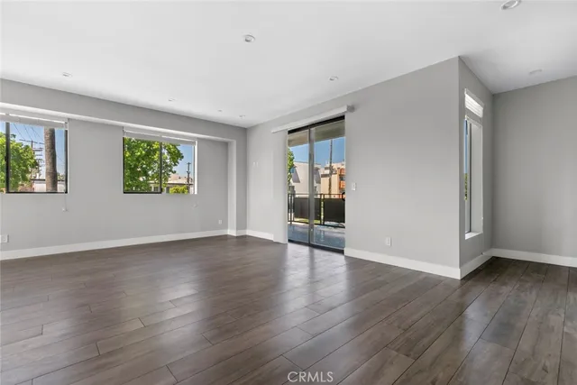 a view of an empty room with window and wooden floor