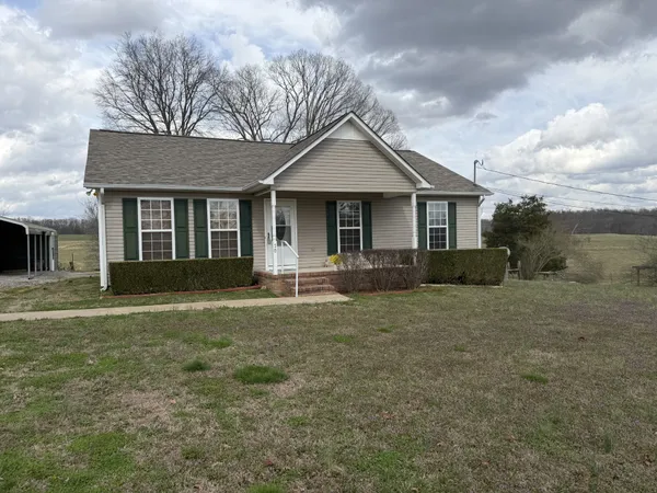a front view of house with yard and trees in the background