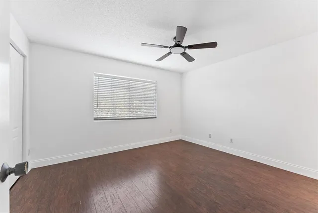 an empty room with wooden floor fan and windows