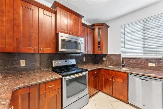 a kitchen with granite countertop a sink stove and microwave