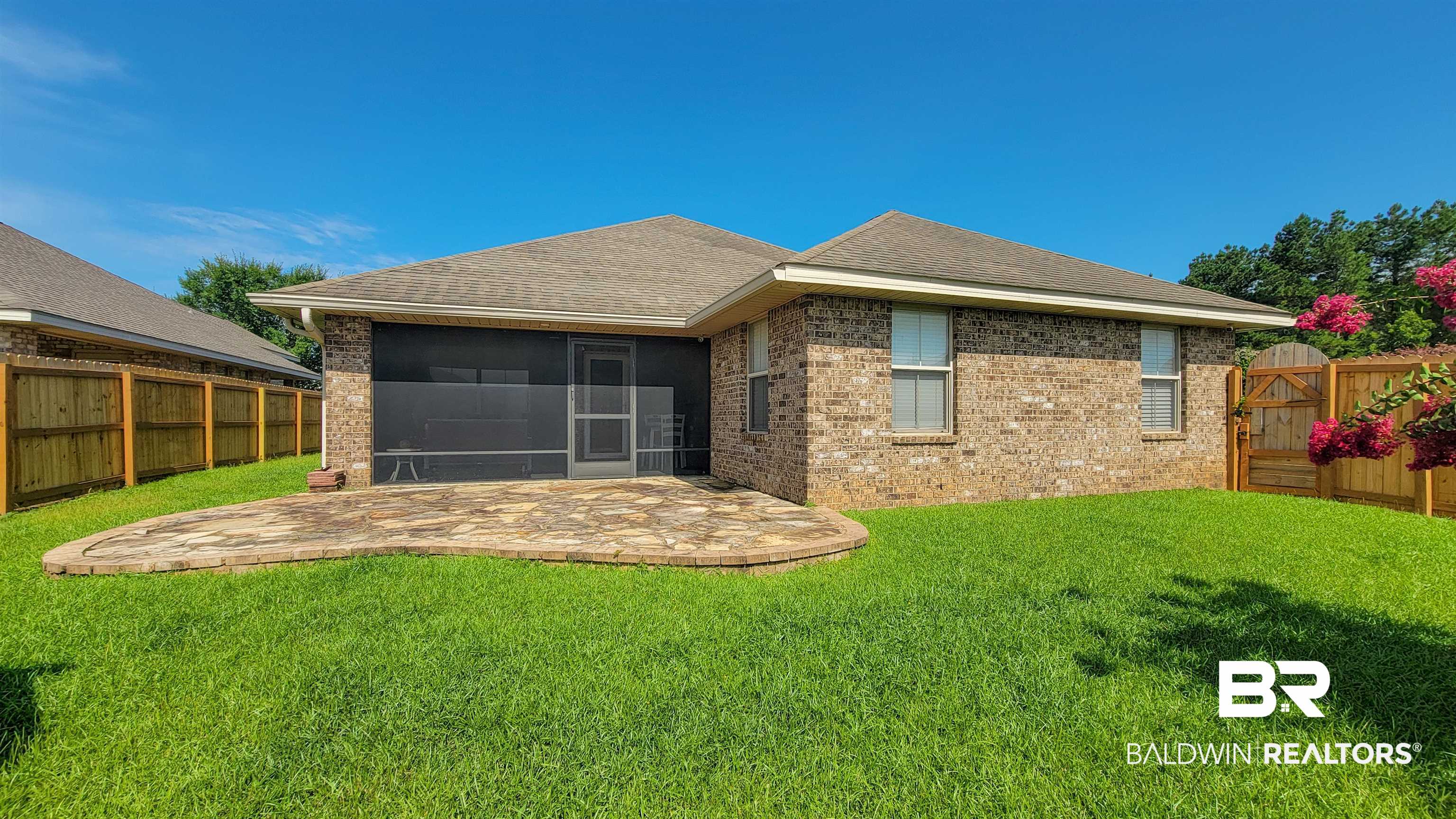 1704 Arcadia Drive Foley, AL 36535 - Photo 47 of 52 Back of property with a sunroom, a patio area, a fenced backyard, brick siding, and a shingled roof