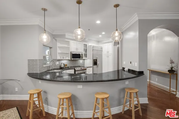 a kitchen with stainless steel appliances granite countertop a stove a sink a refrigerator a center island a dining table and chairs