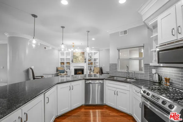 a kitchen with stainless steel appliances granite countertop a sink a stove top oven a counter space and cabinets