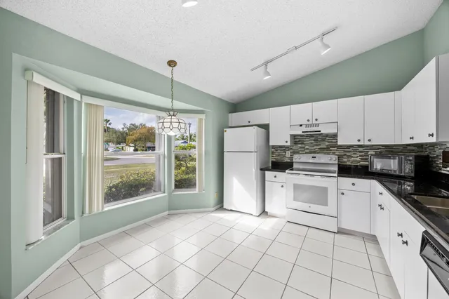 a kitchen with granite countertop white cabinets and appliances