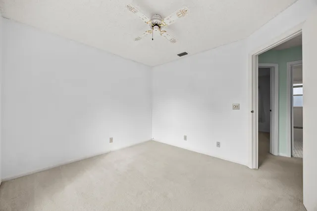 a view of an empty room with window and cabinet area