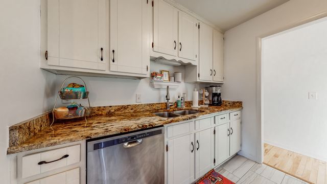 a kitchen with stainless steel appliances granite countertop a sink a stove and white cabinets