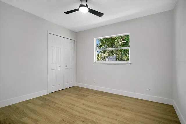 a view of an empty room with wooden floor and a window