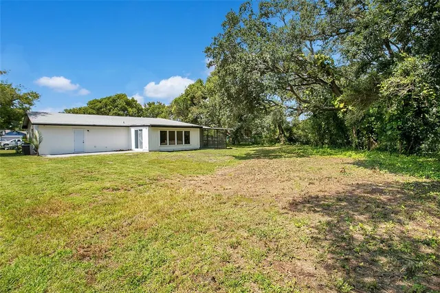 a view of a house with a yard and a large tree