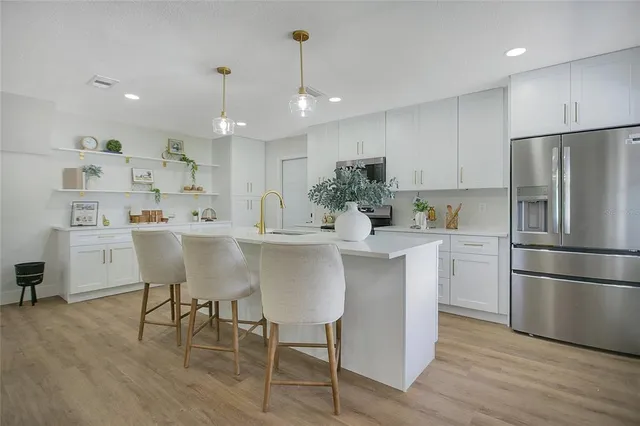 a kitchen with kitchen island white cabinets and stainless steel appliances