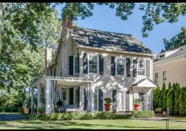 a view of a white house with a yard and potted plants