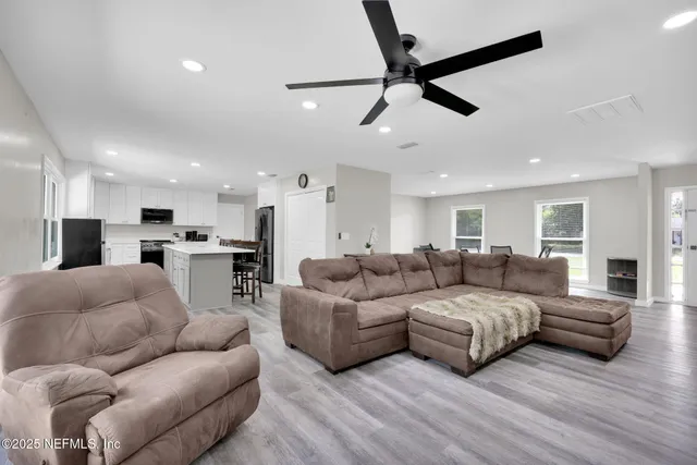 a living room with furniture kitchen view and a window