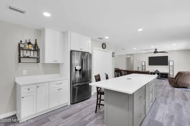 a kitchen with a refrigerator a microwave oven a sink a dining table and chairs