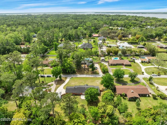 an aerial view of residential houses with outdoor space and trees
