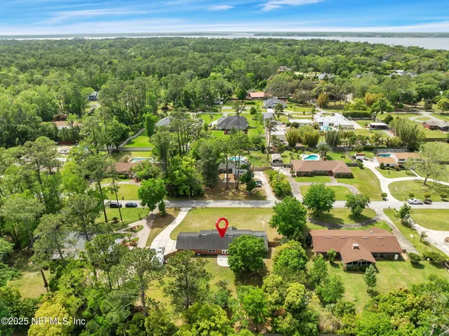 an aerial view of residential houses with outdoor space and trees