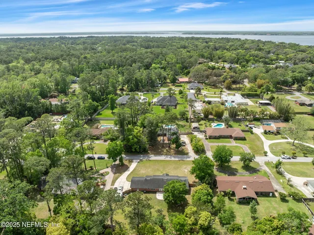 an aerial view of residential houses with outdoor space and trees