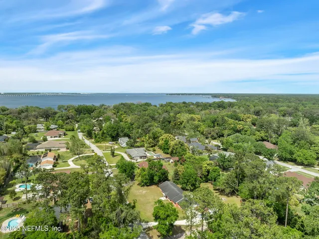 an aerial view of residential houses with outdoor space and trees