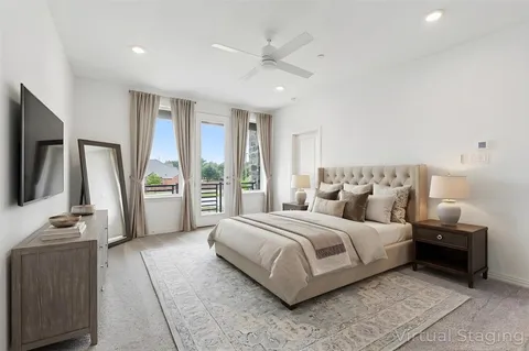 a spacious bedroom with a bed and a flat tv screen
