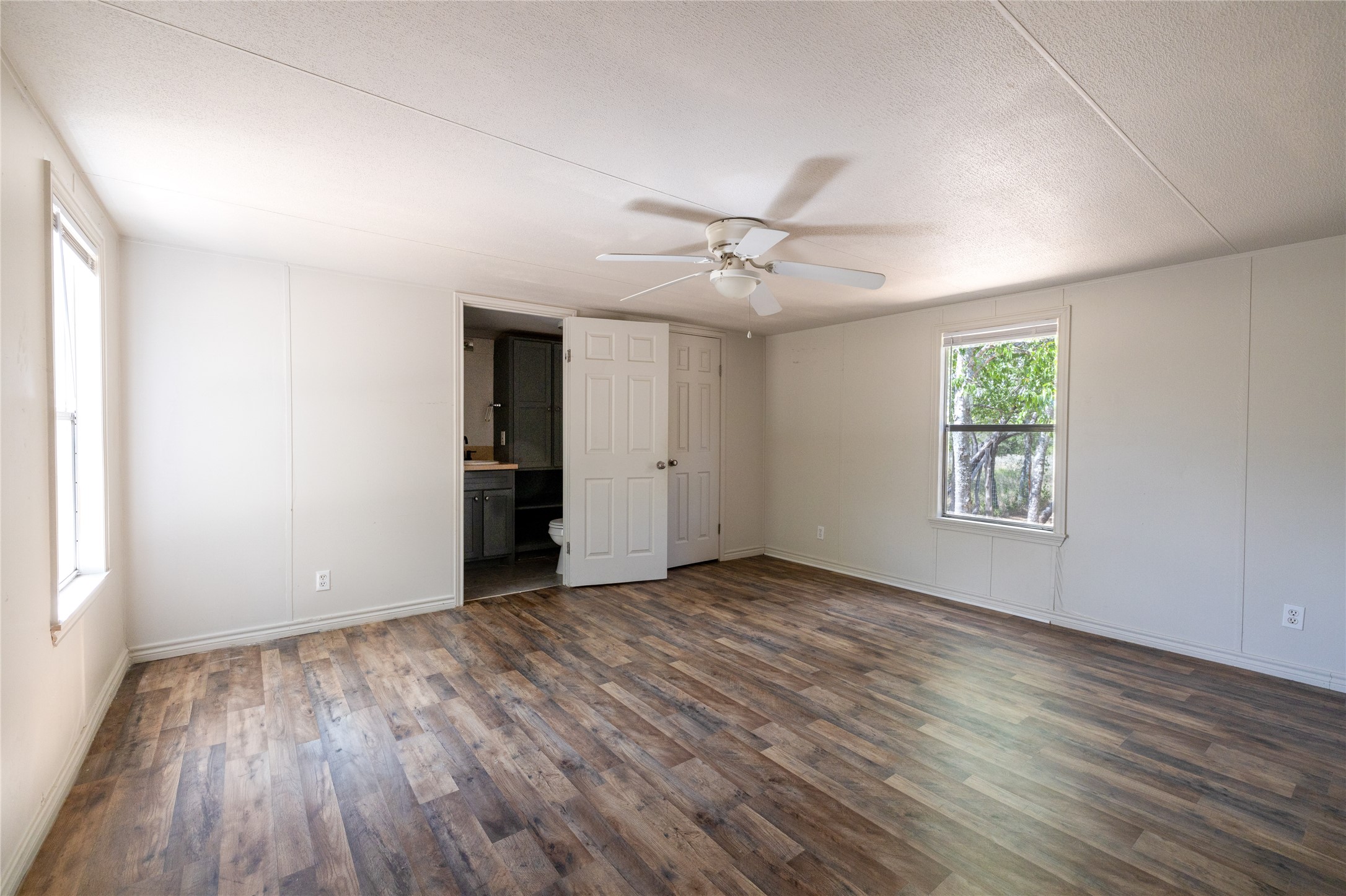 1265 Bugtussle Lane Lockhart, TX 78644 - Photo 5 of 16 an empty room with wooden floor chandelier fan and windows
