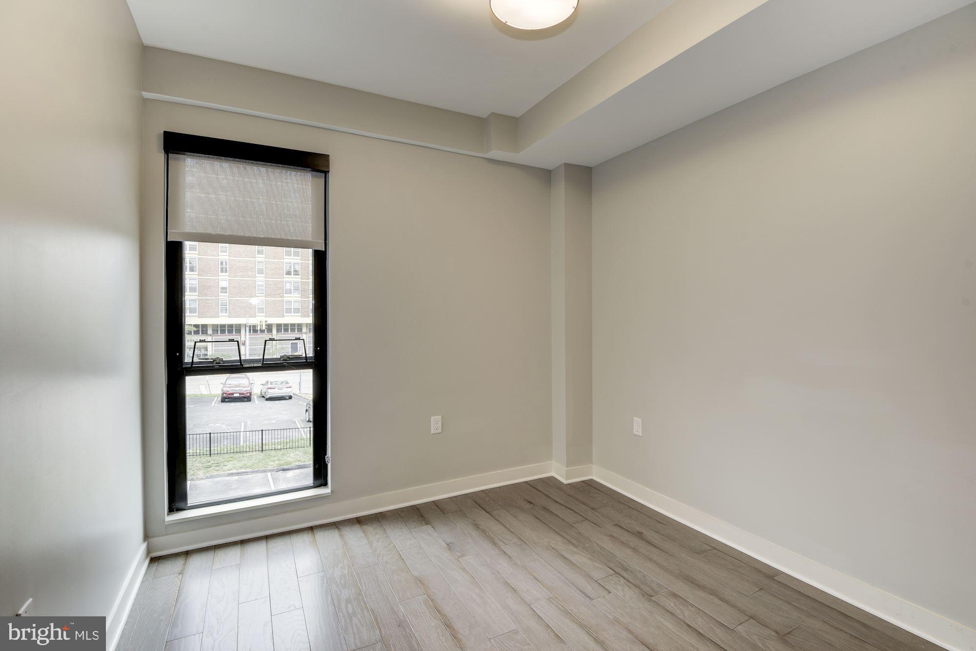 1320 Fenwick Lane, Unit 202 Silver Spring, MD 20910 - Photo 7 of 19 a view of an empty room with wooden floor and a window