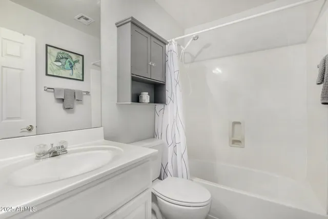 a bathroom with a bathtub shower sink vanity mirror and toilet