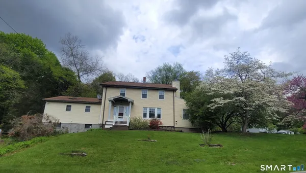 a view of a white house with a big yard and large trees