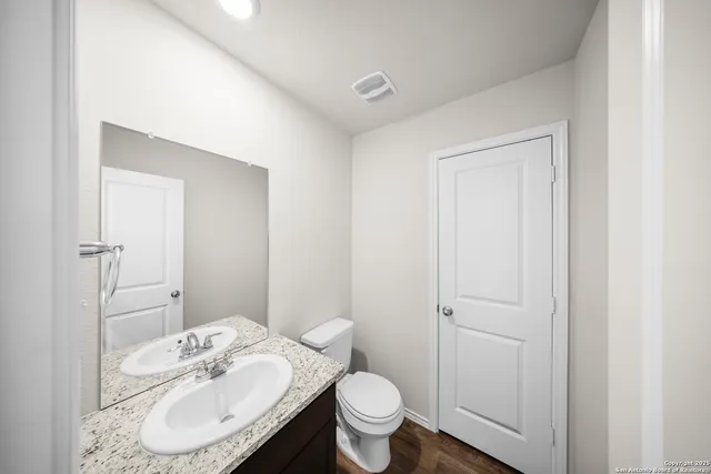 a bathroom with a granite countertop sink toilet and mirror