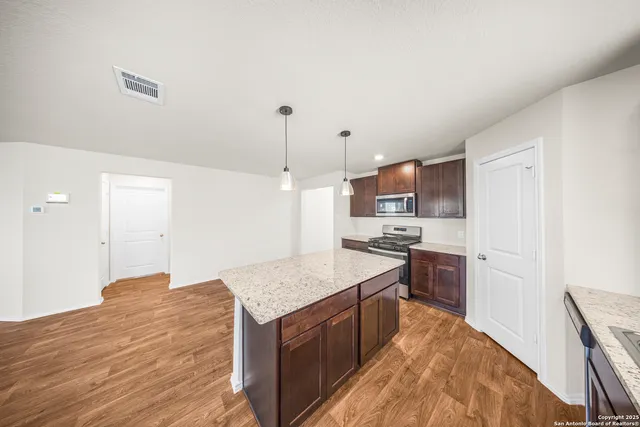 a kitchen with stainless steel appliances granite countertop a sink a stove and a wooden floors