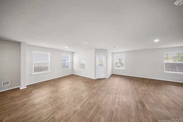 an empty room with wooden floor and windows