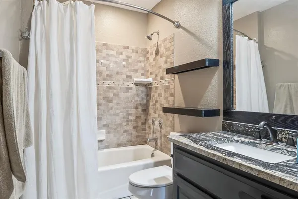 a bathroom with a granite countertop sink toilet and shower