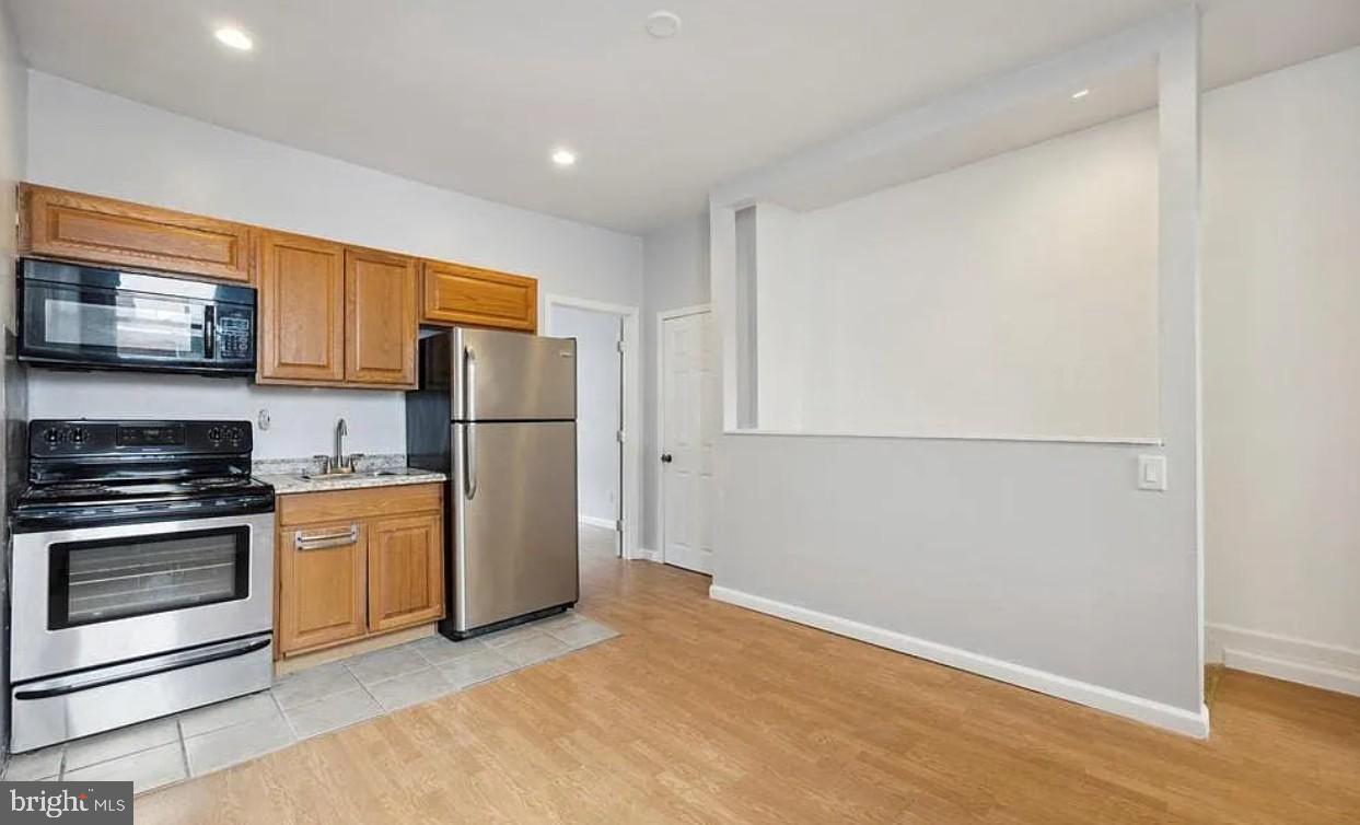 a kitchen with stainless steel appliances granite countertop a refrigerator a stove a sink and a microwave