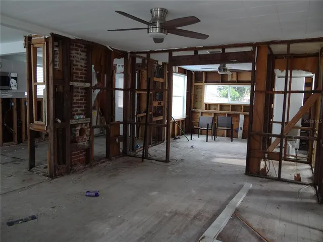 an empty room with ceiling fan and windows